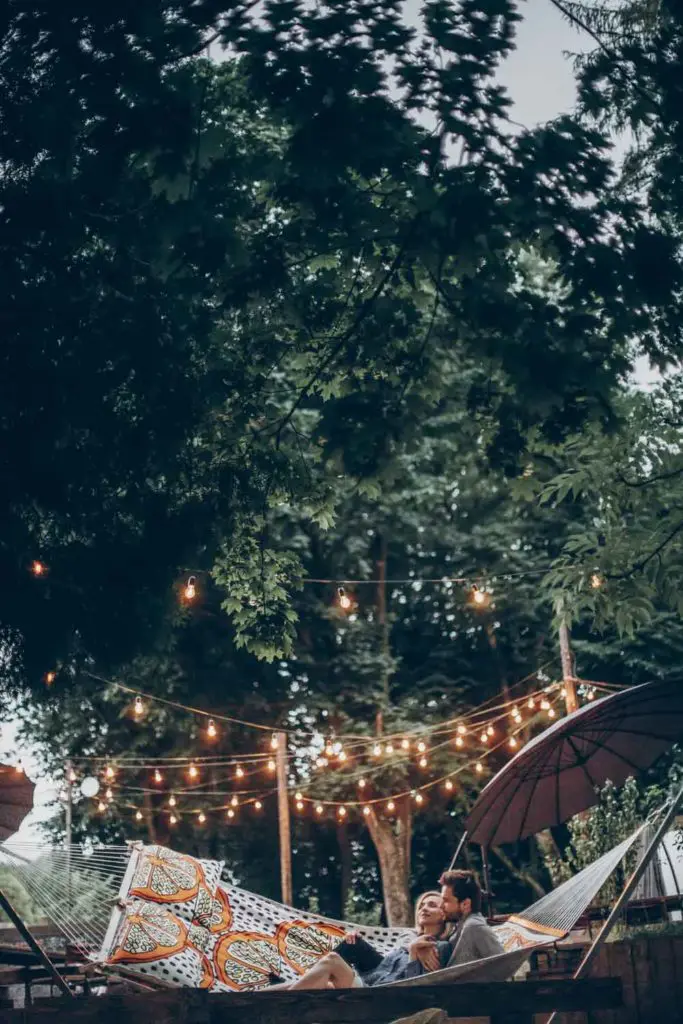 Staycation idea: a couple in a backyard oasis in a hammock.