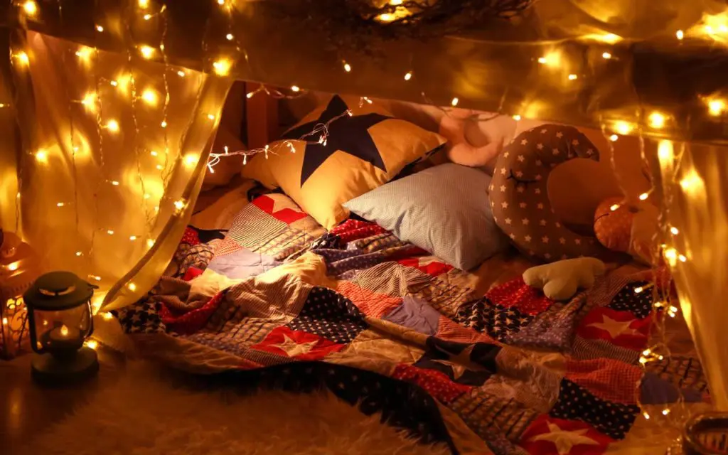 Staycation idea: a fort inside with beautiful string lights.