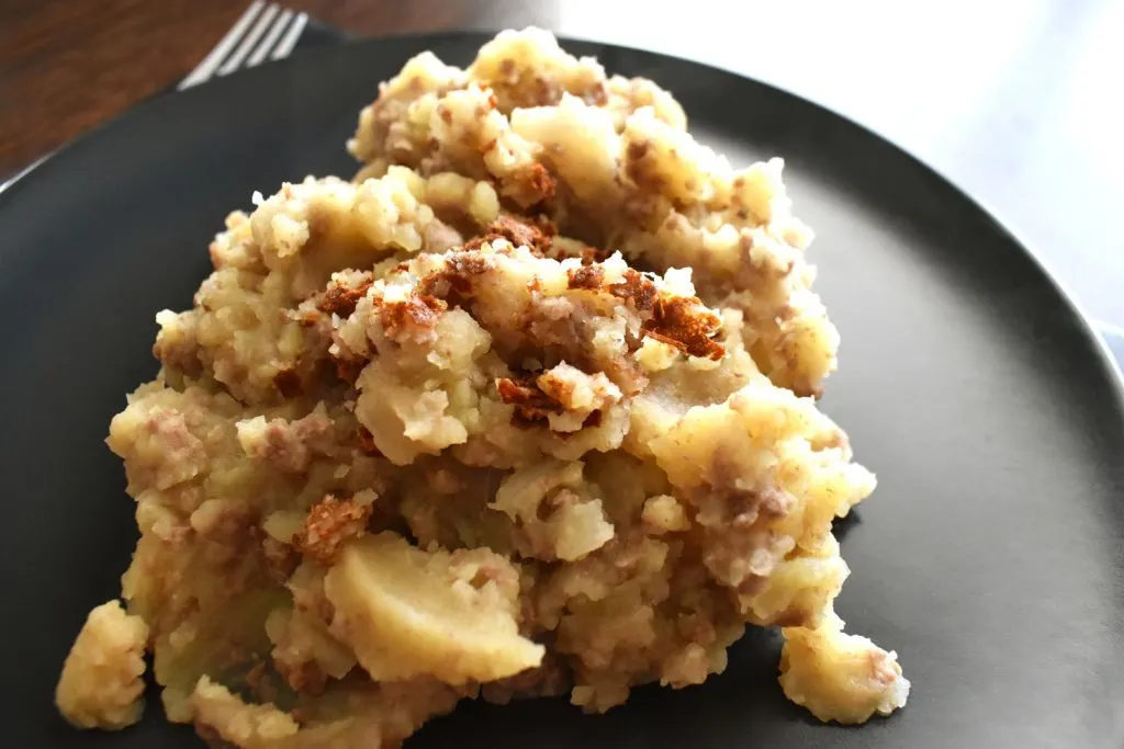 Stovies on a black plate.