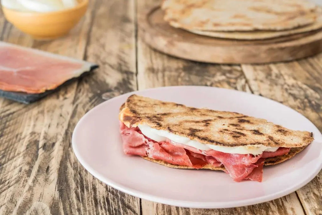 Piadina with scquacquerone on a white plate on a rustic table
