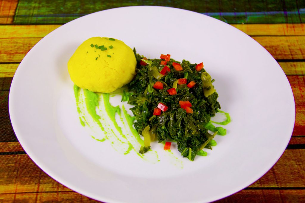 Sukuma Wiki (Collard Greens/Kale) and ugali on a white dinner plate.