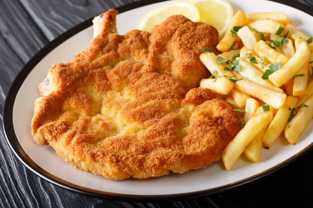 Milanesa (Veal Schnitzel) with a side of french fries and lemon slices for garnish.