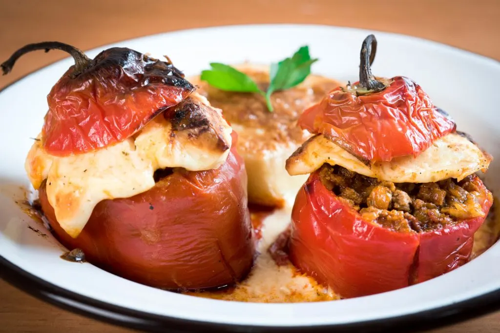 Two Rocoto Relleno (Stuffed Scotch Bonnet Peppers) in a shallow white bowl.