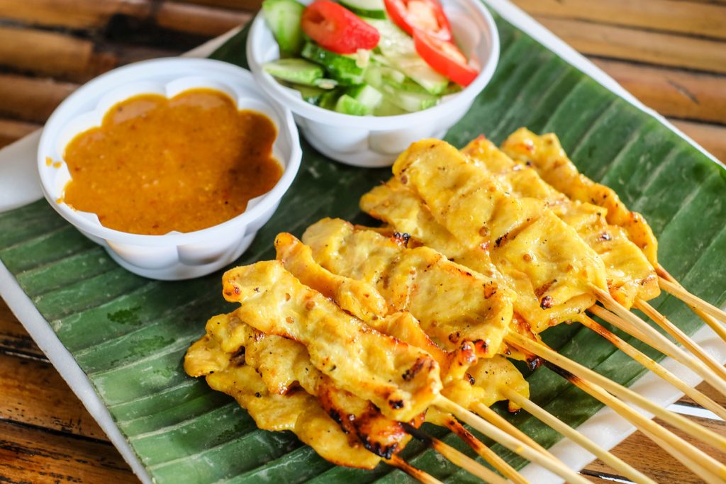 Thai grilled pork skewers with satay sauce and a small side salad.