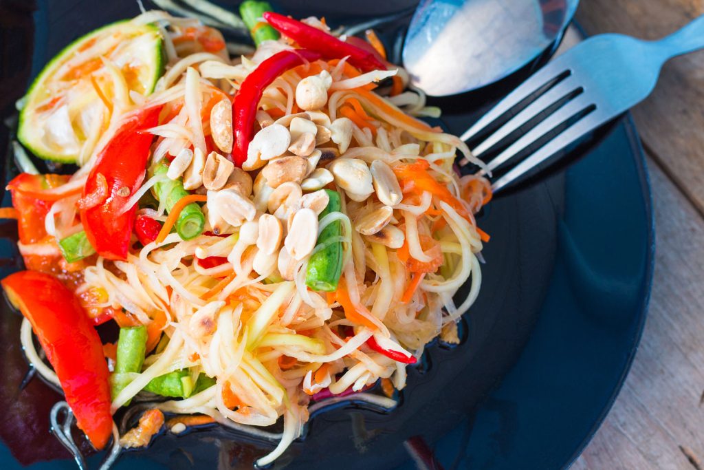 Green papaya salad served beautifully on a dark plate.