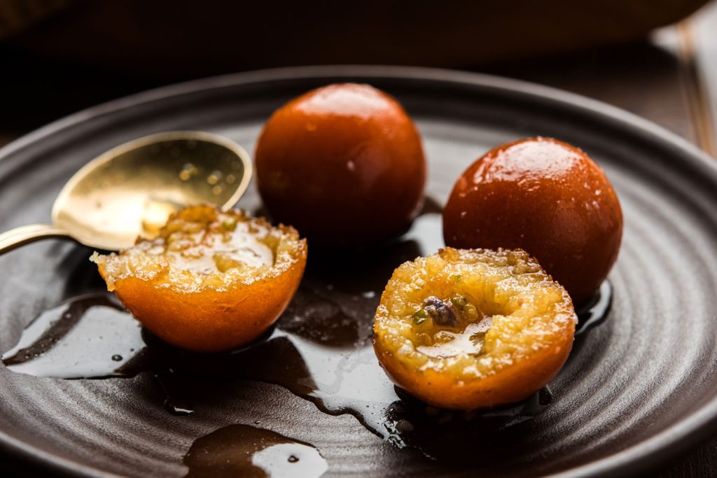 Gulab Jamun balls in syrup served on a plate.