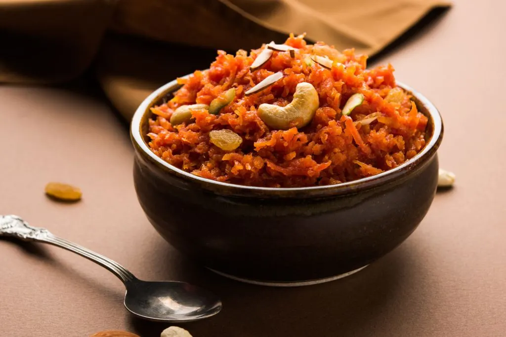 A bowl of Carrot Halwa, topped with cashews and raisins.