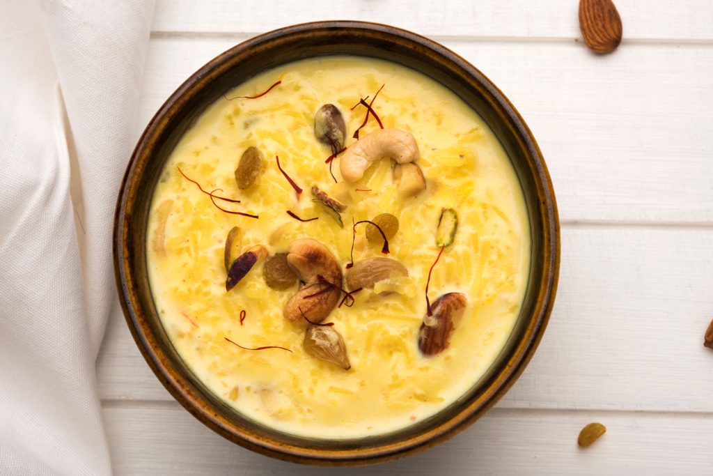 Golden Indian dessert kheer topped with nuts, raisins, and strands of saffron.