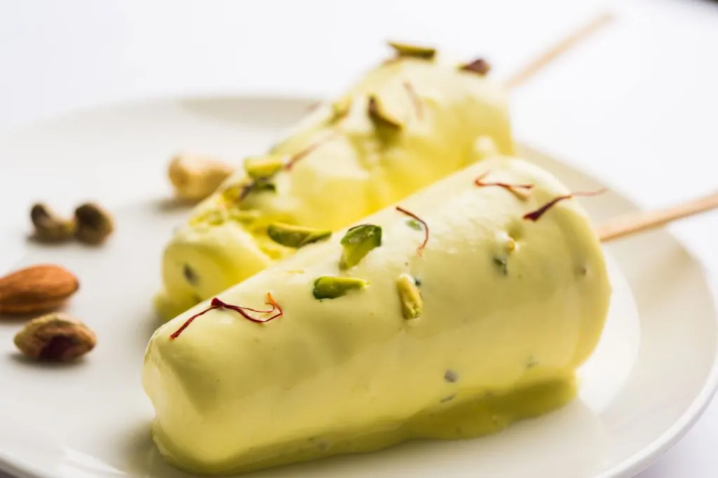 Kulfi, Indian ice cream on a stick, served on a plate.