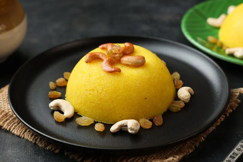 A golden Indian dessert called Kesari, served topped with nuts and raisins.