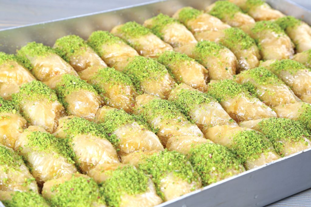 Sütlü Nuriye (Milky Nuriye) in a tray with pistachio crumbs on top.