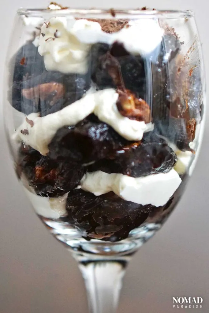 Walnut-stuffed prunes layered with whipped cream in a glass.