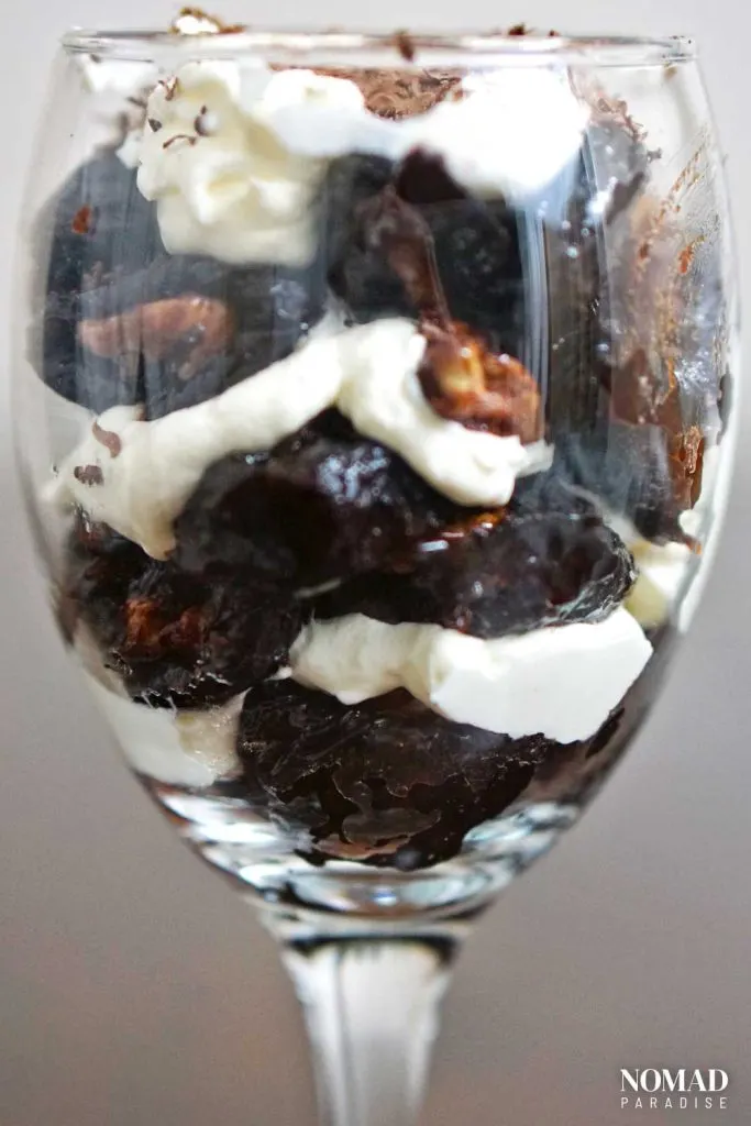 Walnut-stuffed prunes with whipped cream in a glass.