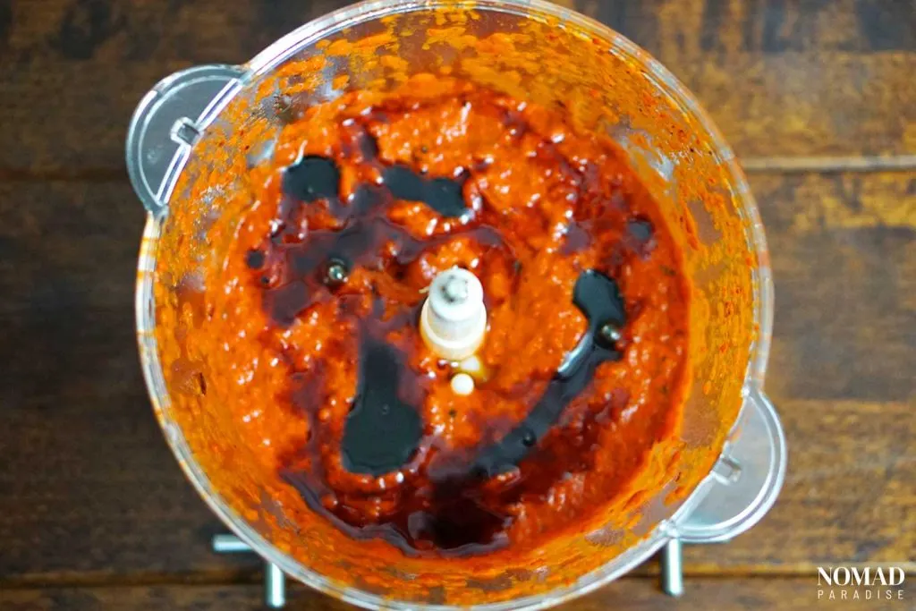 Muhammara recipe step by step (peeled roasted peppers, garlic, tomato paste with spices, and pomegranate molasses in the food processor).
