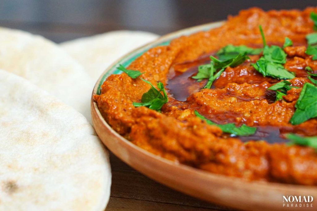 Muhammara topped with parsley and pomegranate molasses served with pita.