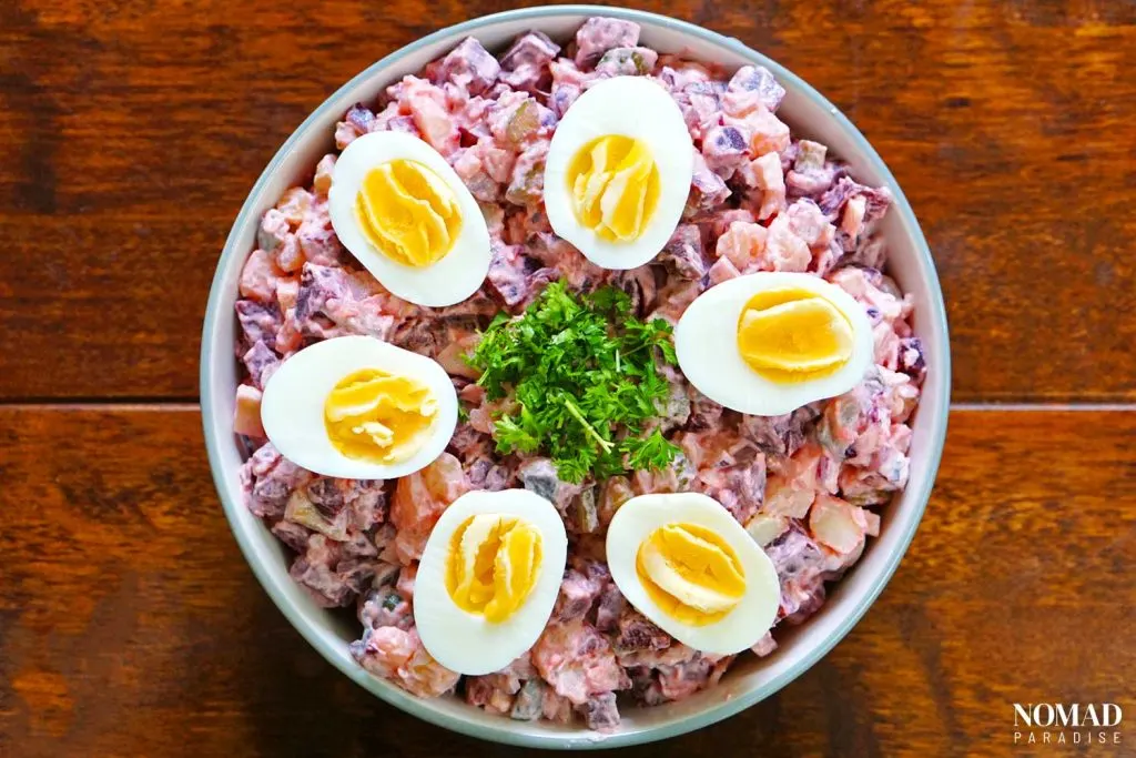 Final potato and beet salad with halved boiled eggs and parsley on top.