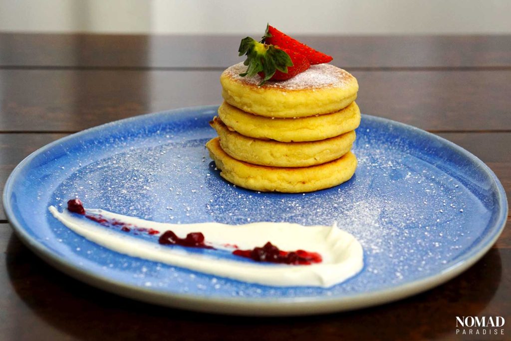 Cottage Cheese Pancakes(Syrniki) on a blue plate with sour cream and jam
