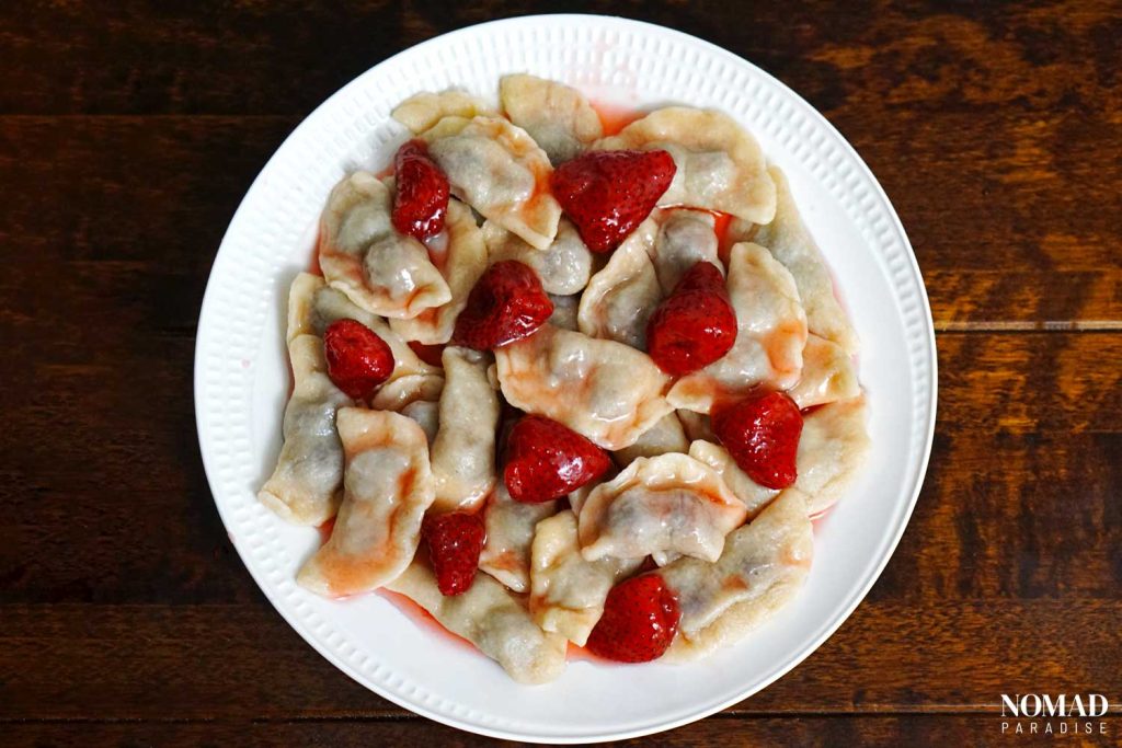 Varenyky with strawberry varenye on a white plate.