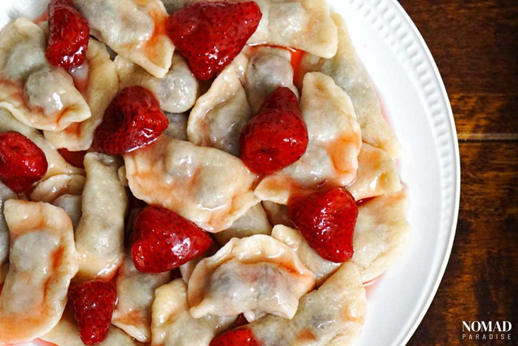 Varenyky with strawberry varenye on a white plate.