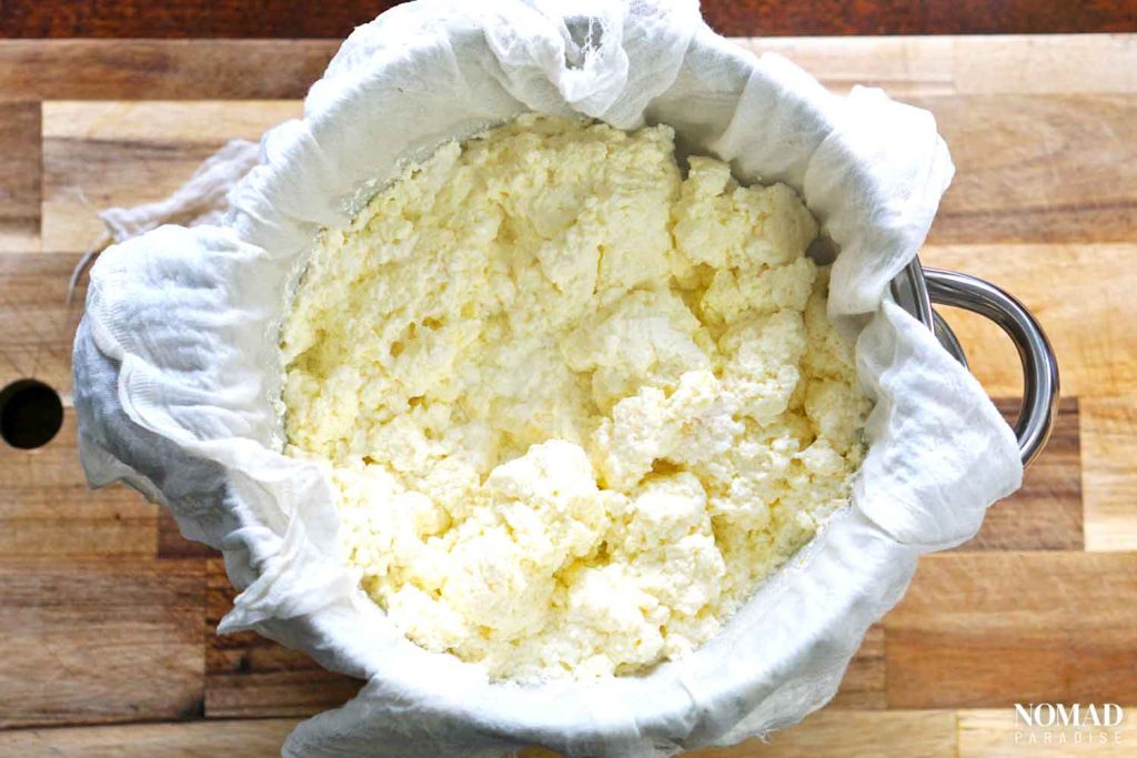 Homemade Farmer's Cheese Recipe step-by-step (cheese curds in the cheesecloth covered strainer).