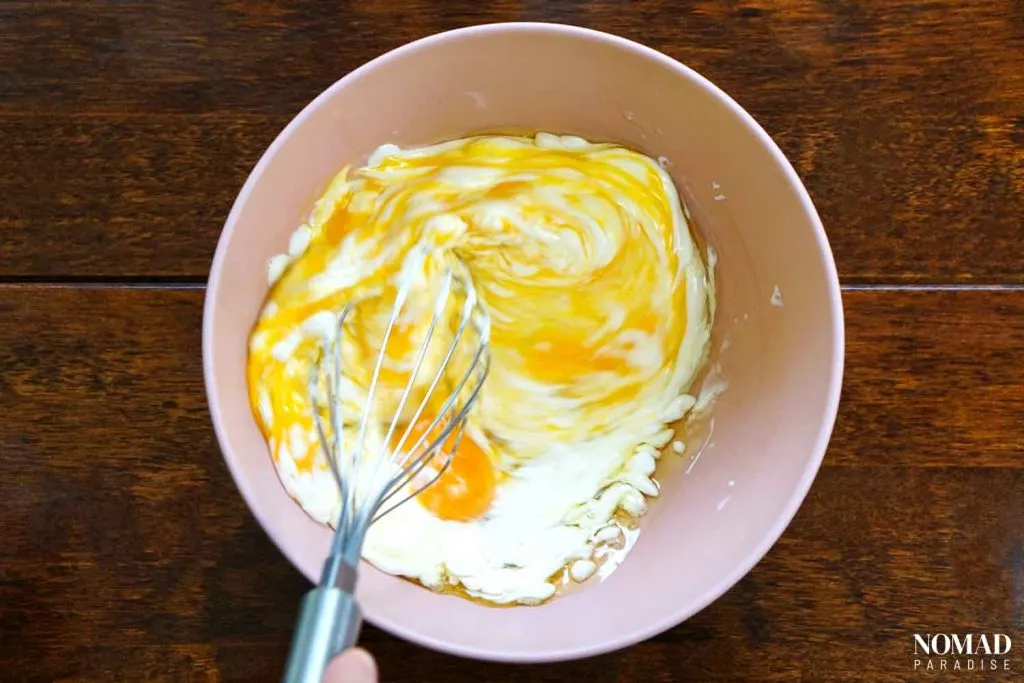 Banitsa Recipe Step by Step (mixing the eggs, oil, yogurt, and baking soda with a whisk).