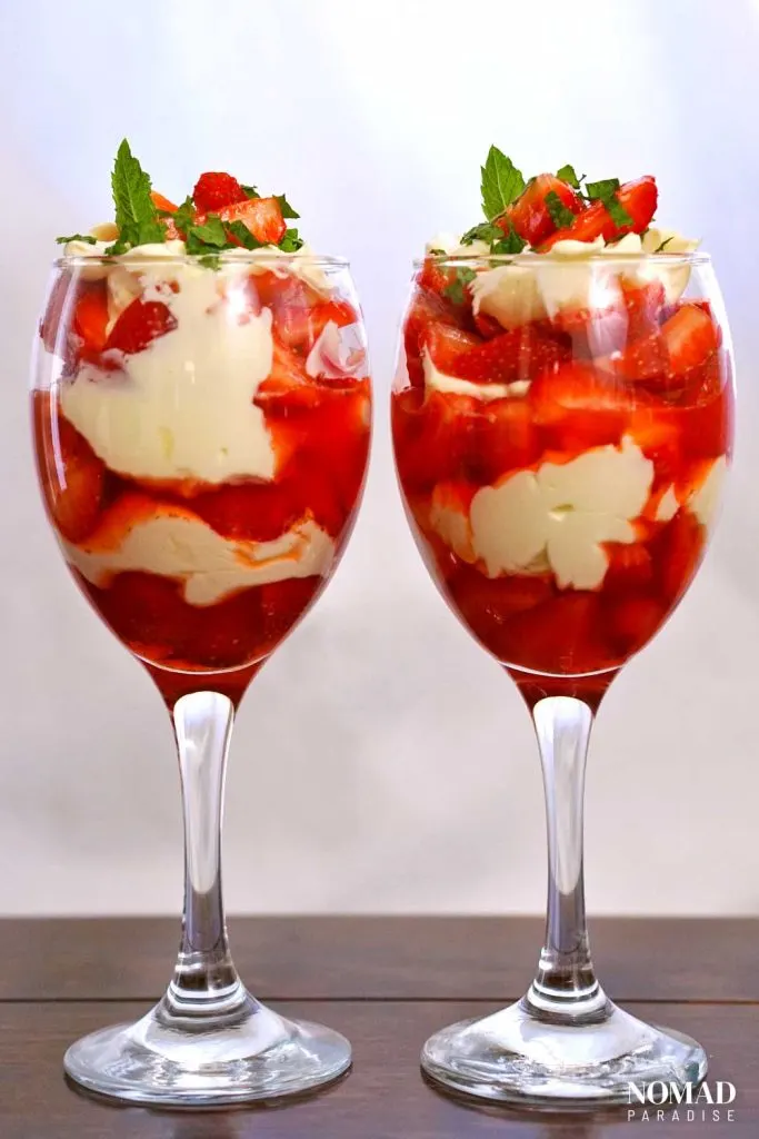 Strawberries and cream in two glasses side by side, decorated with mint.