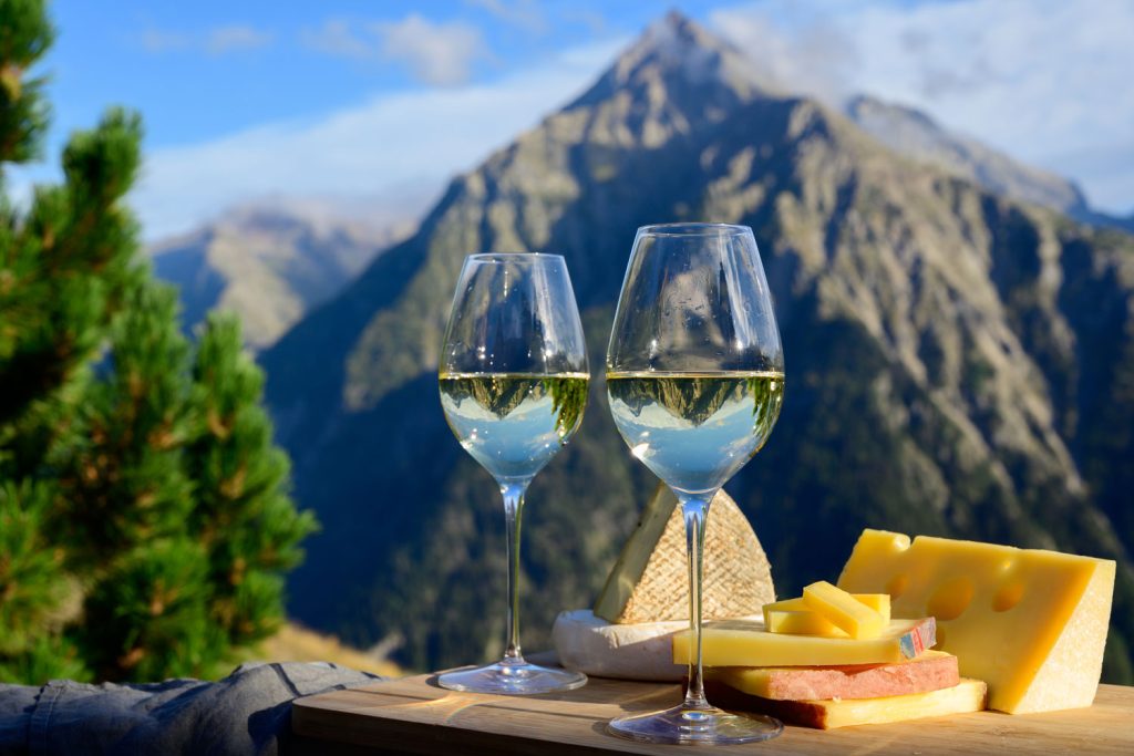 Emmental de Savoie cheese and two glasses of white wine.