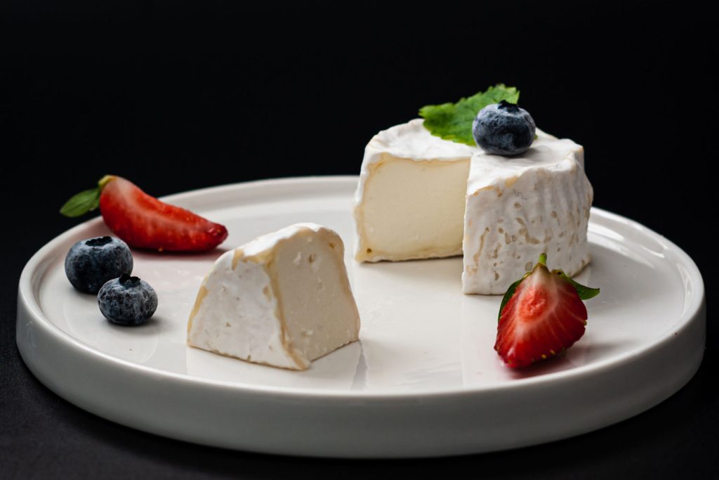 Chaource cheese and some berries on a plate.