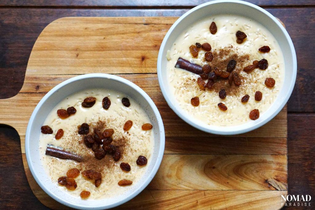 Arroz con leche in bowls with ground cinnamon and raisins on top.
