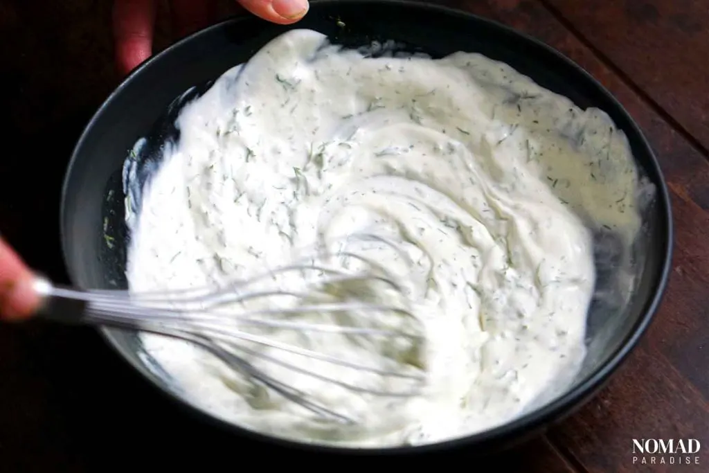 Mizeria (Polish Cucumber Salad) step-by-step (mixing the sour cream with other ingredients without the cucumber).