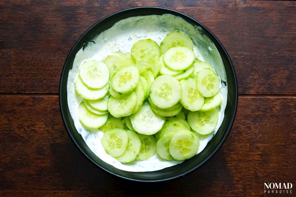 Mizeria (Polish Cucumber Salad) step-by-step (adding the cucumbers to the sour cream mixture).