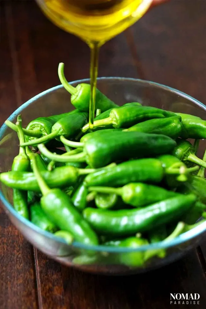 Spanish Padron Peppers Step-by-Step (adding the oil to the peppers in a large bowl).