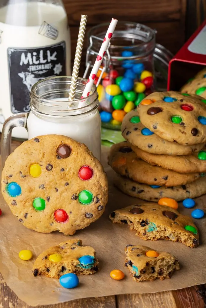 Stack of M&M cookies and milk next to them