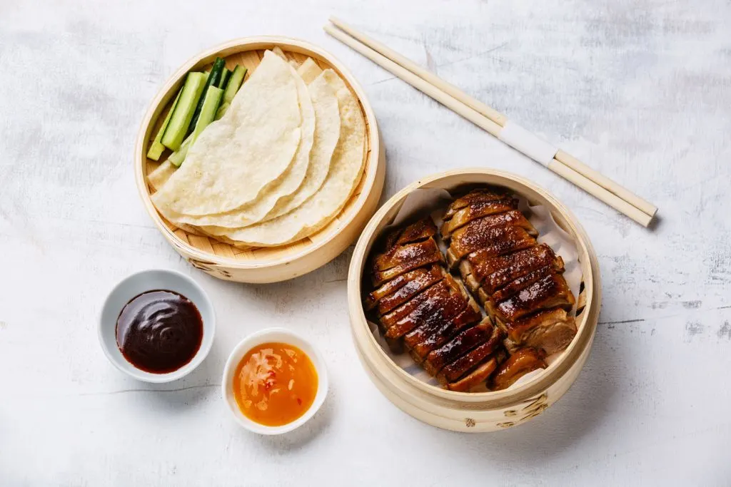 Sliced peking duck with sweet bean sauce, cucumber, and pancakes.