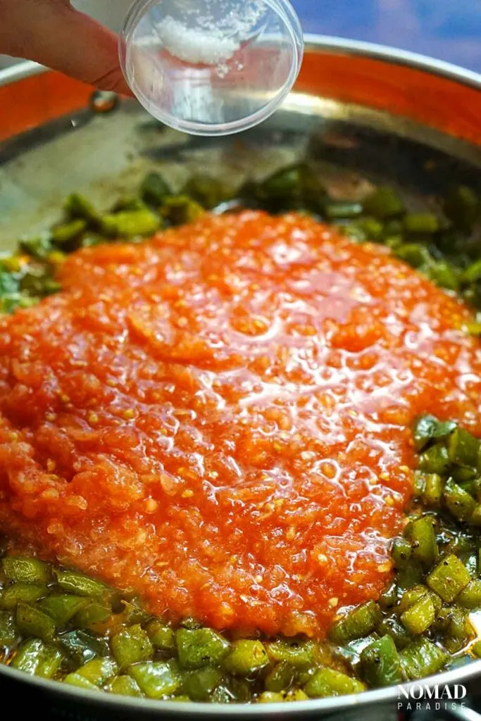 Adding the pinch of sugar to the grated tomatoes and the sauteed diced peppers.