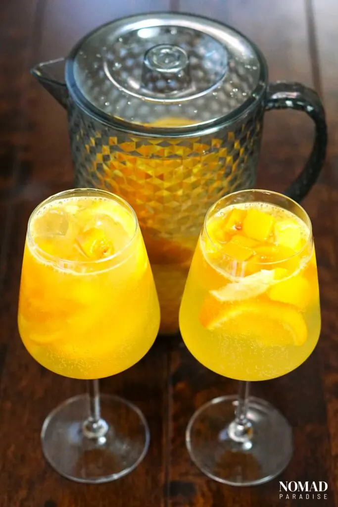 Two glasses and a pitcher of sparkling white wine sangria