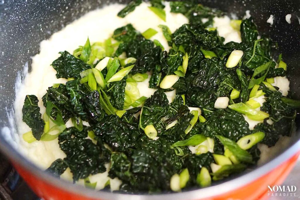 Adding kale and chopped spring onions to the colcannon.